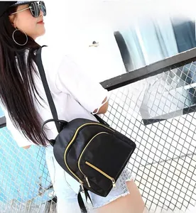 Detail shot of a black waterproof backpack with gold zippers shown on model's shoulder