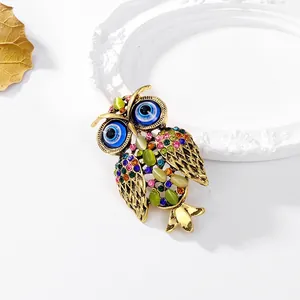 Luxury owl brooch with multicolored crystals and evil eye detail in vintage gold finish
