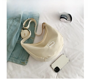 Détail du sac bandoulière en nylon crème avec sangle et petit porte-monnaie rond