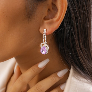 Close-up of a silver-tone teardrop earring with purple stone and micro-pave diamonds