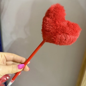 Close-up of a creative red ballpoint pen with a soft plush heart decoration on top
