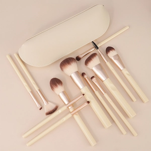Dettaglio di 12 pennelli da trucco color crema con ghiere in oro rosa e custodia
