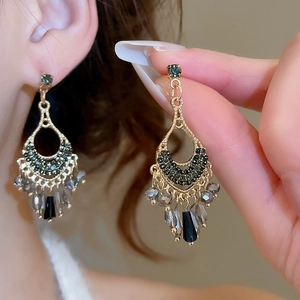 Detailed view of vintage crystal tassel earrings with gold filigree and dark gemstones