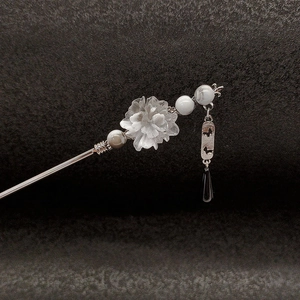Macro detail of ancient style hair stick with translucent white flower and beaded tassel