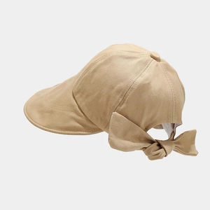 Detail of a beige cotton sun hat featuring a decorative large bow on the back and twill texture