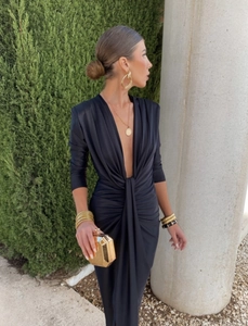Détail d'une élégante robe en satin noir col V avec bijoux dorés et pochette de soirée