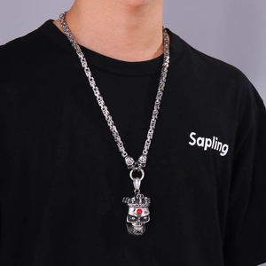 Detail of punk skeleton pendant with red gemstone crown and thick king chain on neck