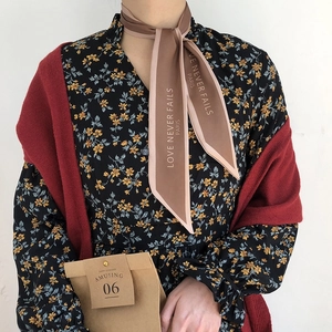 Detail of French silk scarf with Love Never Fails text tied as hair accessory