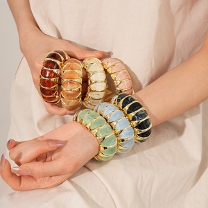 Close-up of colorful resin stretch bracelets with gold spacers on a female model