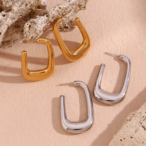 Detail view of U-shaped gold and silver earrings with hammered texture on a rock
