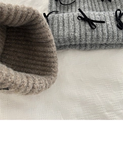 Close-up of grey and brown chunky knit beanies with decorative black velvet bows