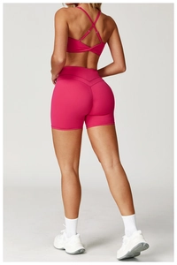 Dettaglio del reggiseno sportivo rosso rosa con spalline incrociate e pantaloncini bici