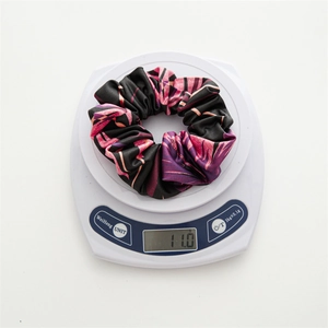 Floral satin scrunchie with pink leaf patterns on a scale showing 11.0g weight