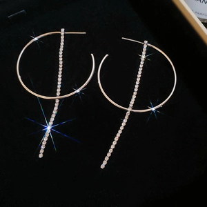 Dettaglio di eleganti orecchini a cerchio in oro 18K con lunghe nappe di zirconi