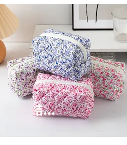 Detailed view of quilted floral cosmetic bags in four pastel colors on a white desk