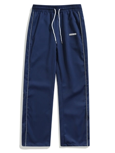 Detail of dark blue joggers featuring a white drawstring and side piping with a fabric patch