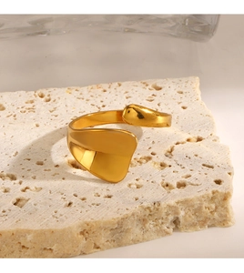 Macro shot of irregular geometric gold-plated open ring on white stone base