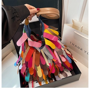 Detail view of a colorful fringed leather shoulder bag presented in a premium gift box