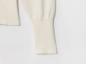 Close-up of premium white knit sweater ribbed cuffs and fine texture details
