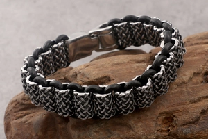 Close-up of a men's woven leather bracelet on dark wood for a rugged aesthetic