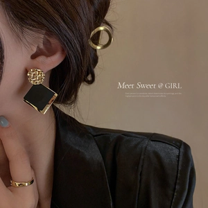 Geometric diamond square earrings in black and gold finish worn by a model