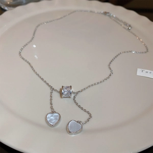 Detailed close-up of heart-shaped cat eye pendants on a silver necklace in a ceramic dish