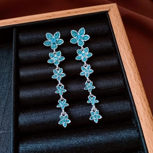 Close-up of vintage flower drop earrings with blue cubic zirconia on black velvet tray