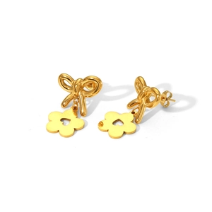 Detail of gold bow earrings with hollow flower pendants on a clean white background
