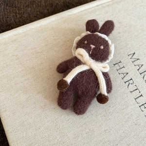 Detailed macro view of the fluffy wool felt texture on a handmade brown bear brooch