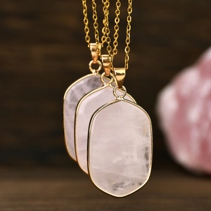Macro shot of three natural rose quartz oval pendants with elegant golden plated edges