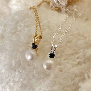 Detail of gold and silver pearl necklaces with black zircon on white knit background