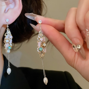 Detail of silver drop earrings with colorful beads, tassels and a teardrop pearl on model
