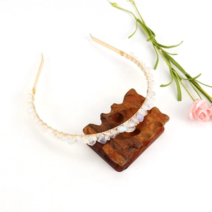 Detail view of handmade golden headband with raw crystal stones on a wooden stand