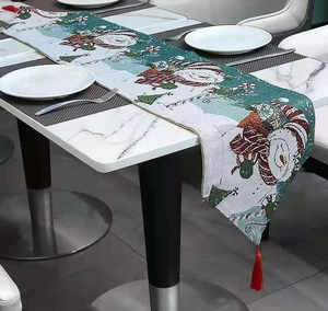 Christmas snowman embroidered table runner with red tassels on a marble table