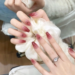 Detail of long coffin nails with red gradient design and delicate cherry accents