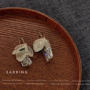 Floral earrings with sheer fabric petals and colorful glass pendants on a wooden tray