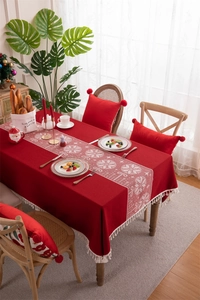 Detail of red Christmas tablecloth featuring white snowflake patterns and elegant fringe trim