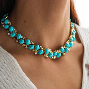 Detail of bohemian gold-tone choker necklace with oval blue resin stone and zircon