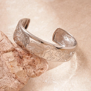 Detail of silver-toned relief engraving on an oval open cuff bracelet over a stone