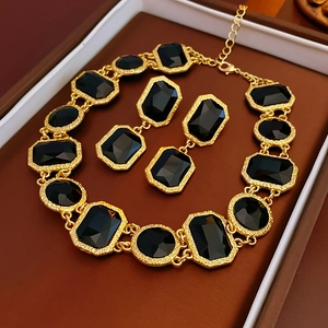 Flat lay of vintage crystal tassel earrings and necklace set on brown leather tray