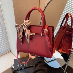 Elegant wine red leather tote bag with silk scarf and gold twist lock on mirror surface
