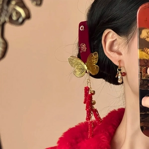 Detail of red velvet butterfly hair clip with gold tassels and matching peanut earrings