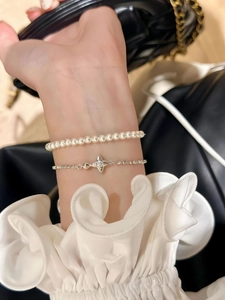 Detail of elegant two-piece bracelet set with white pearls and silver star pendant
