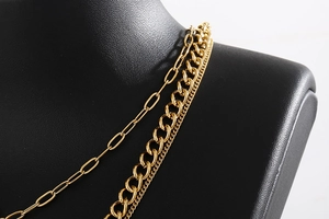 Detailed layered gold necklace featuring paperclip, Cuban, and snake chains on black bust