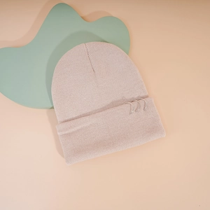 Détail du bonnet en tricot rose avec trois anneaux métalliques argentés sur le bord