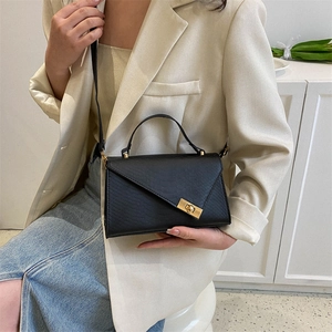 Black crocodile embossed crossbody bag with golden metal clasp shown with stylish outfit