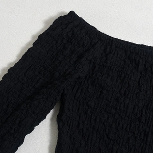 Detail of black 3D textured elastic fabric showing off-shoulder smocked dress design