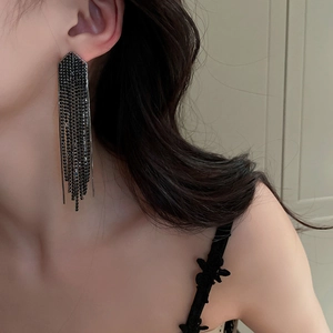 Macro detail of elegant black tassel earrings with sparkling crystals on a model