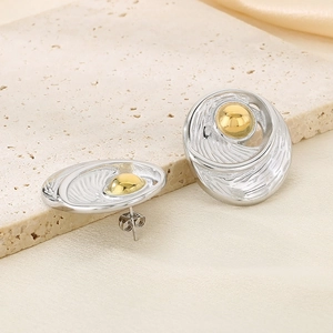 Macro shot of two-tone 18k gold and silver geometric disc earrings on stone base