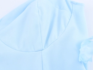 Detailed macro view of light blue dress fabric with mesh texture and 3D floral decoration